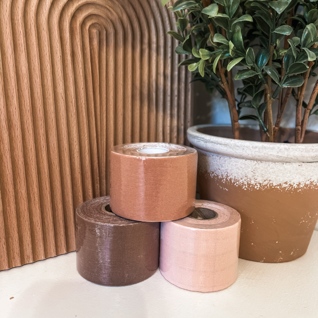 Three rolls of brown tape stacked with a potted plant in the background.