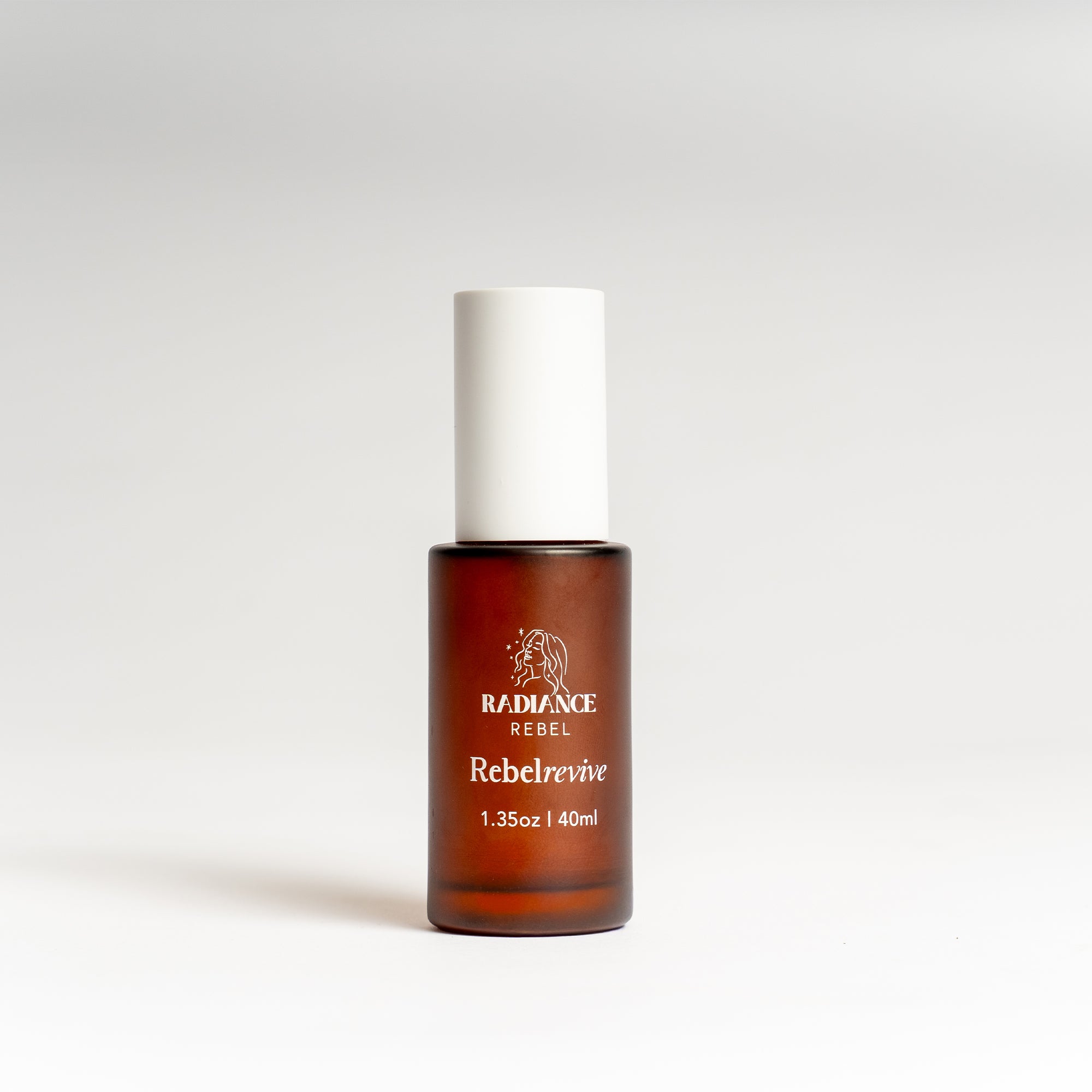 Radiance Rebel Rebelrevive facial serum in an amber brown bottle with a white cap, centered on a light gray background.