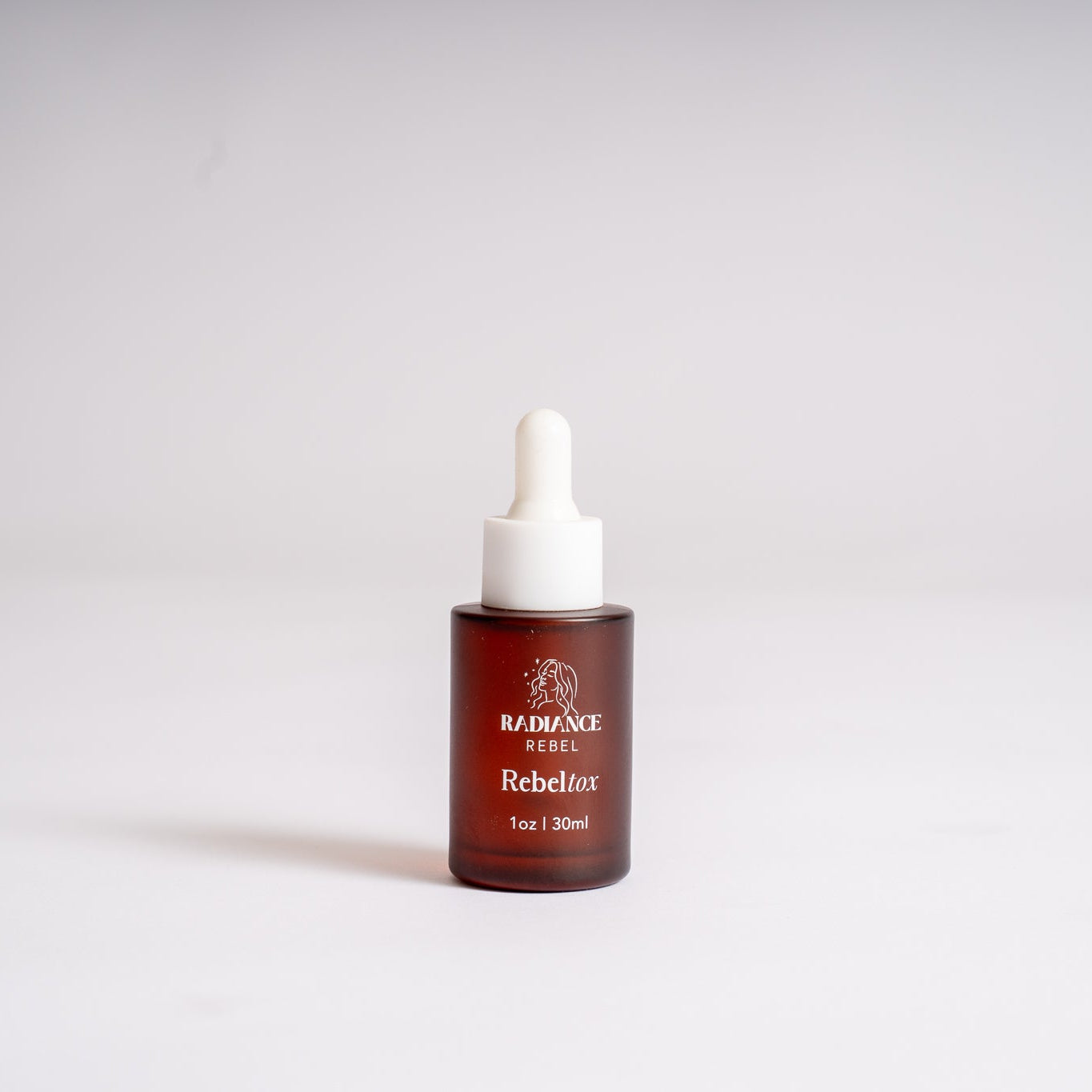 A small amber glass dropper bottle with a white rubber pipette top and white printed text reading 'RADIANCE REBEL Rebeltox' on a clean white background.